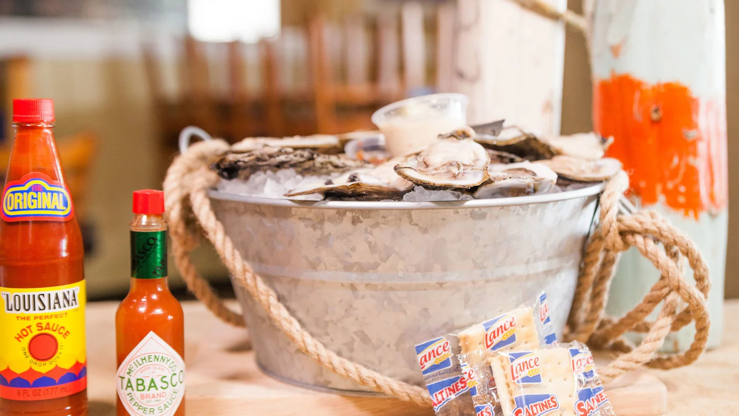 Fresh oysters on ice in a seafood bucket with Louisiana hot sauce