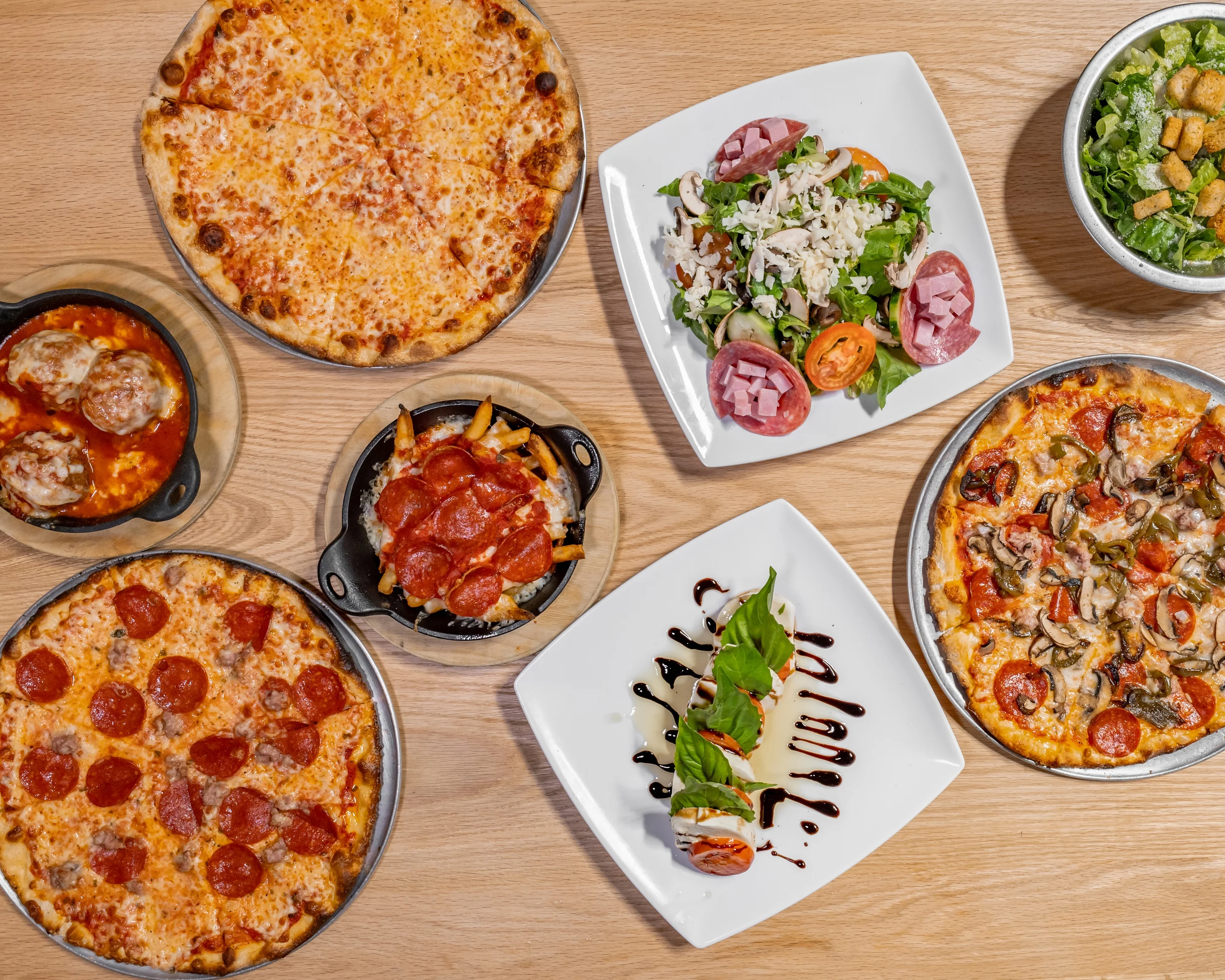 Variety of Italian pizzas and salads on a wooden table