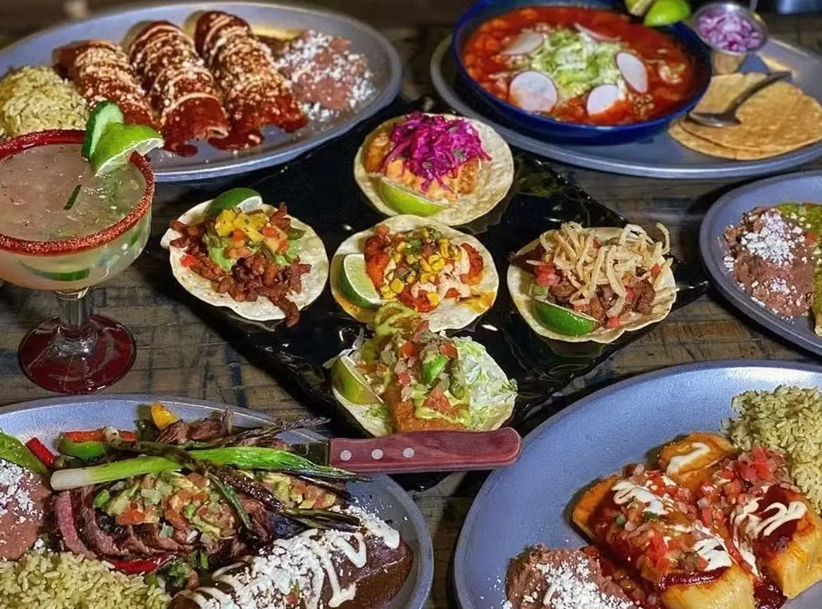 A vibrant spread of Mexican dishes including tacos, enchiladas, and drinks.