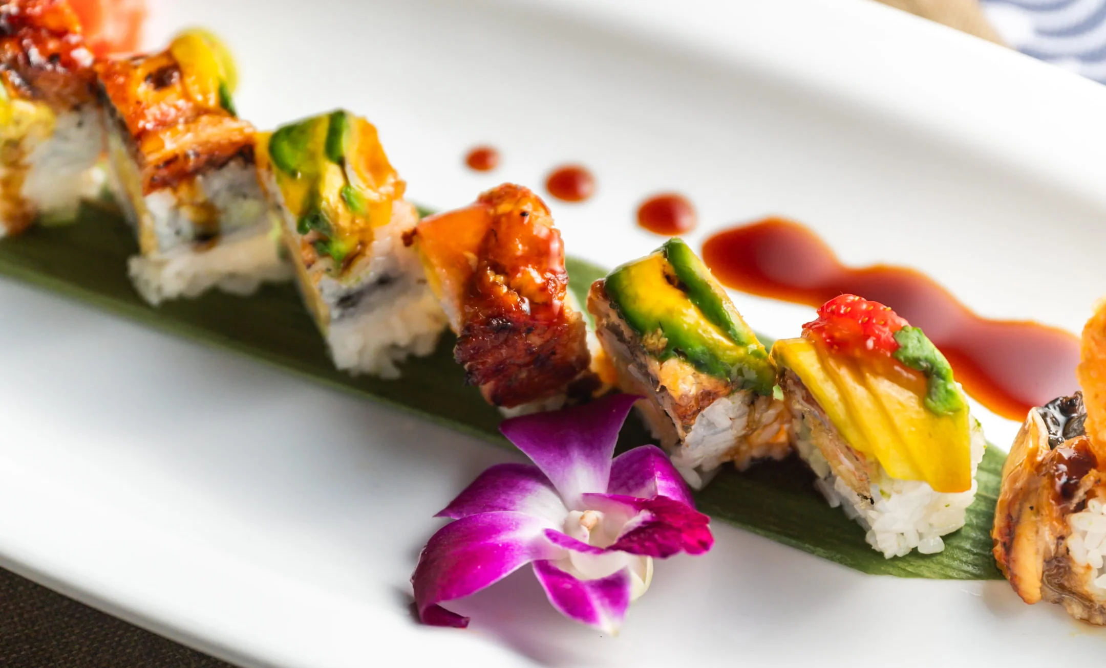 Colorful sushi roll with eel and avocado on a white plate