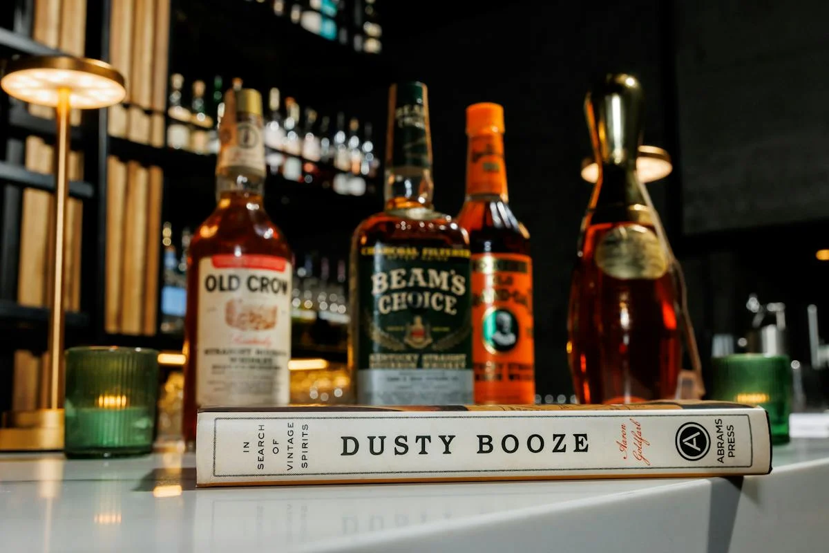 Vintage bourbon bottles and cocktail book displayed on a stylish bar counter