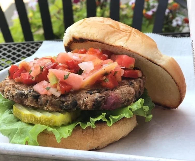 Burger Fresh burger with tomatoes, pickle and lettuce on a tray on a patio table