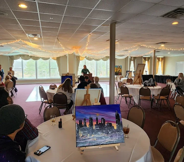 Art event in a spacious banquet hall with attendees and artwork displays