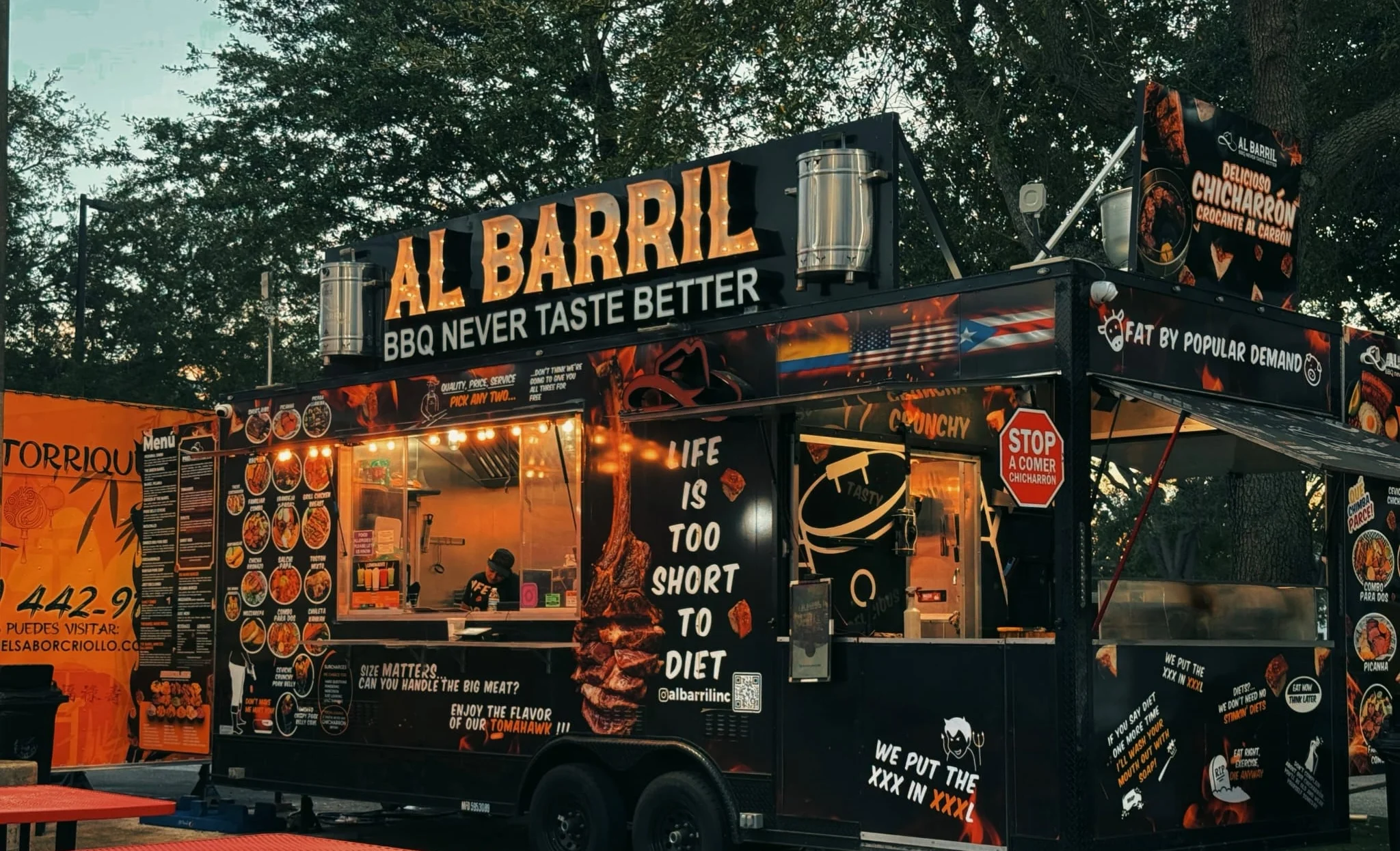 Food truck named Al Barril serving BBQ with vibrant signage and menu.