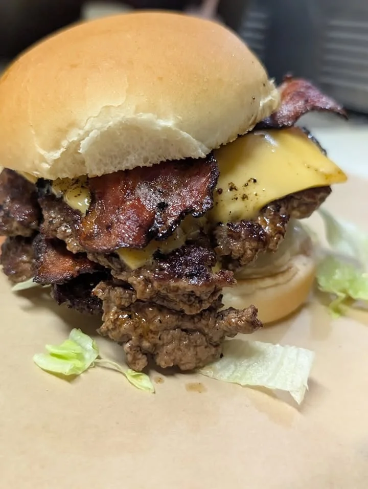 A delicious looking cheeseburger with crispy bacon, melted cheese, and a fresh bun, sitting on a bed of lettuce.