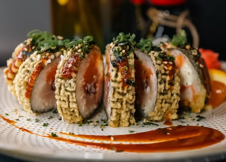 Crispy sushi rolls drizzled with sauce and garnished with herbs