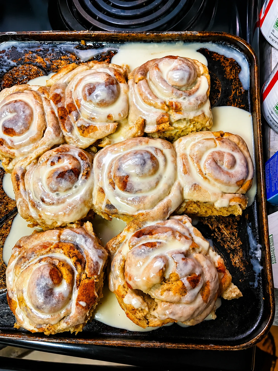 A tray of freshly baked cinnamon rolls drizzled with creamy icing, showcasing their gooey texture.