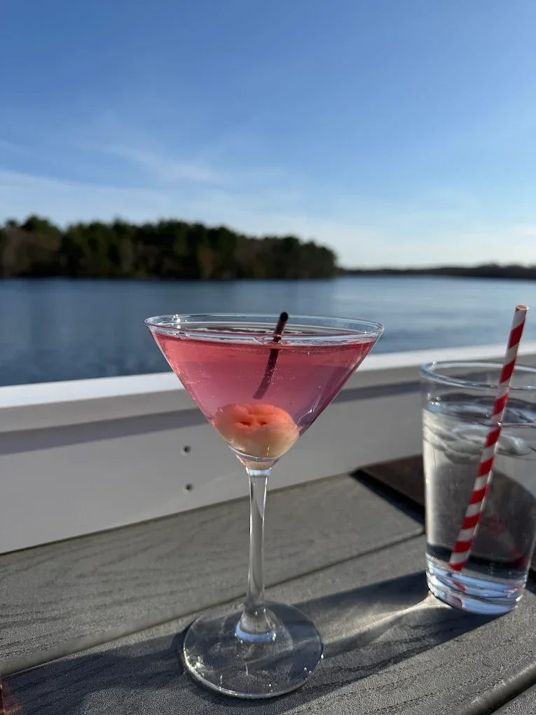 Refreshing pink cocktail with cherry garnish by the lake