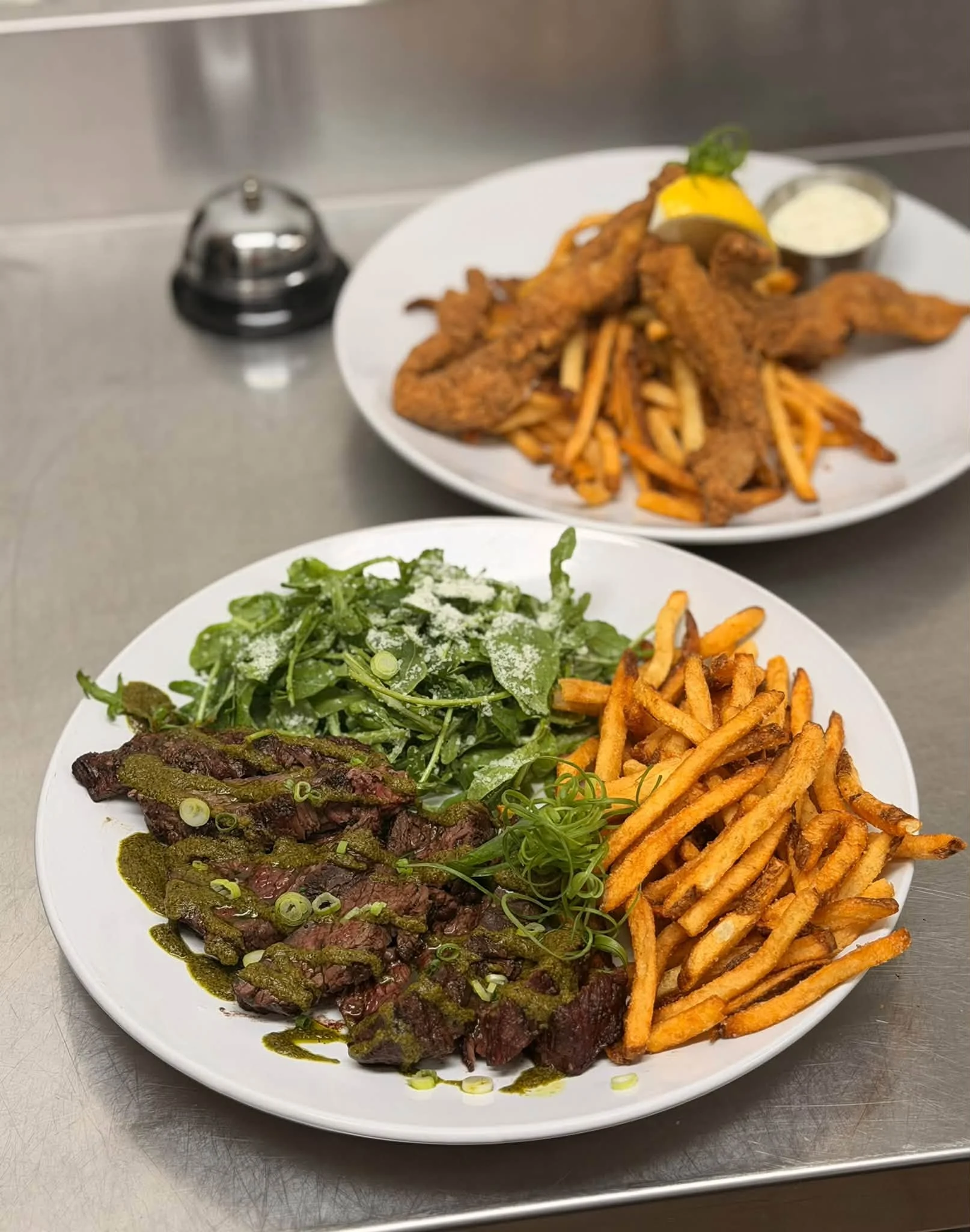 Grilled steak with chimichurri, arugula salad, and crispy fries on a white plate