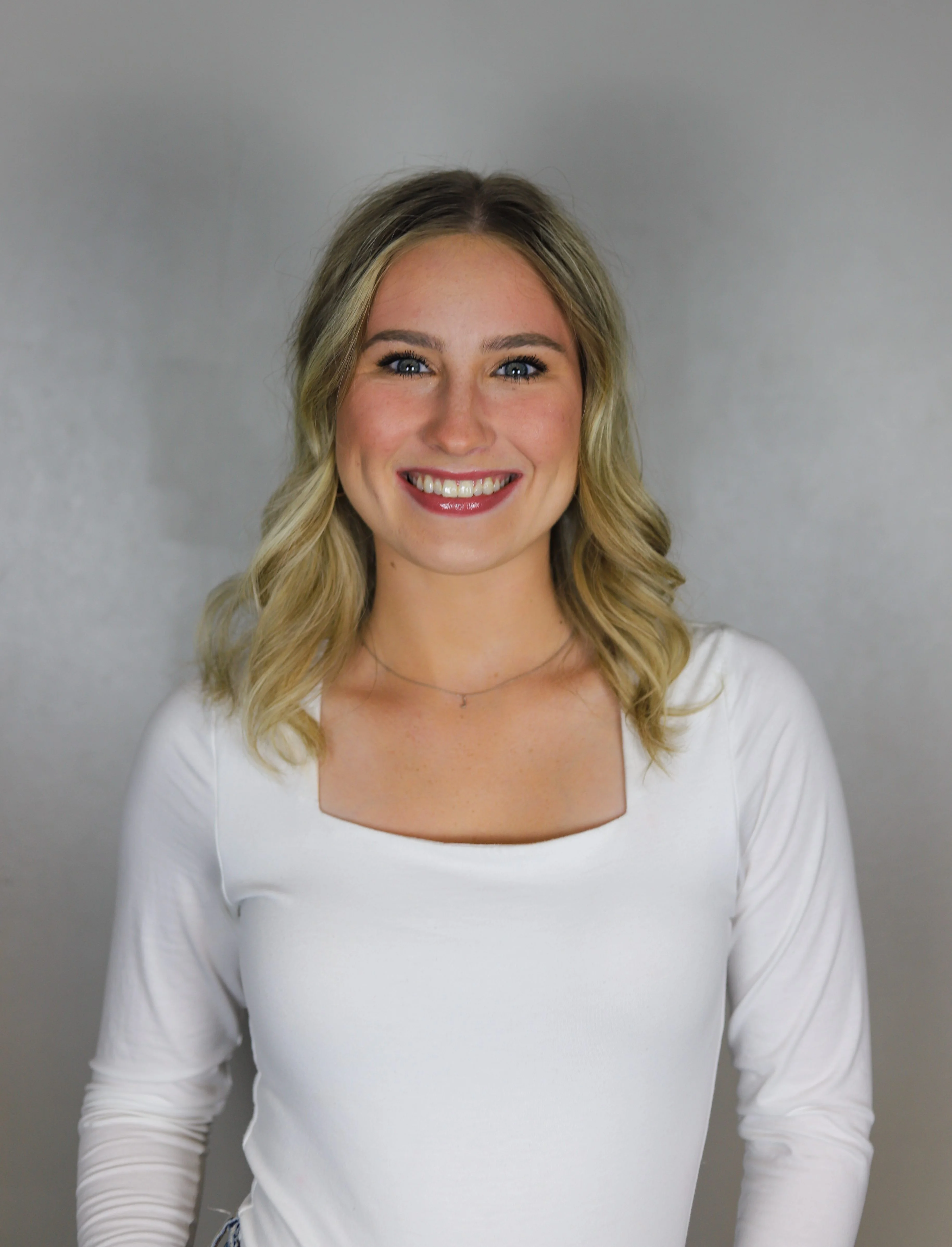 Smiling young woman with blonde hair in a white top