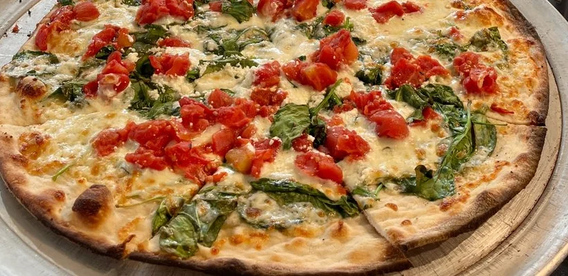 Fresh Margherita pizza topped with spinach and tomatoes