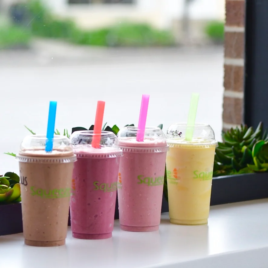 Colorful smoothies in clear cups with straws