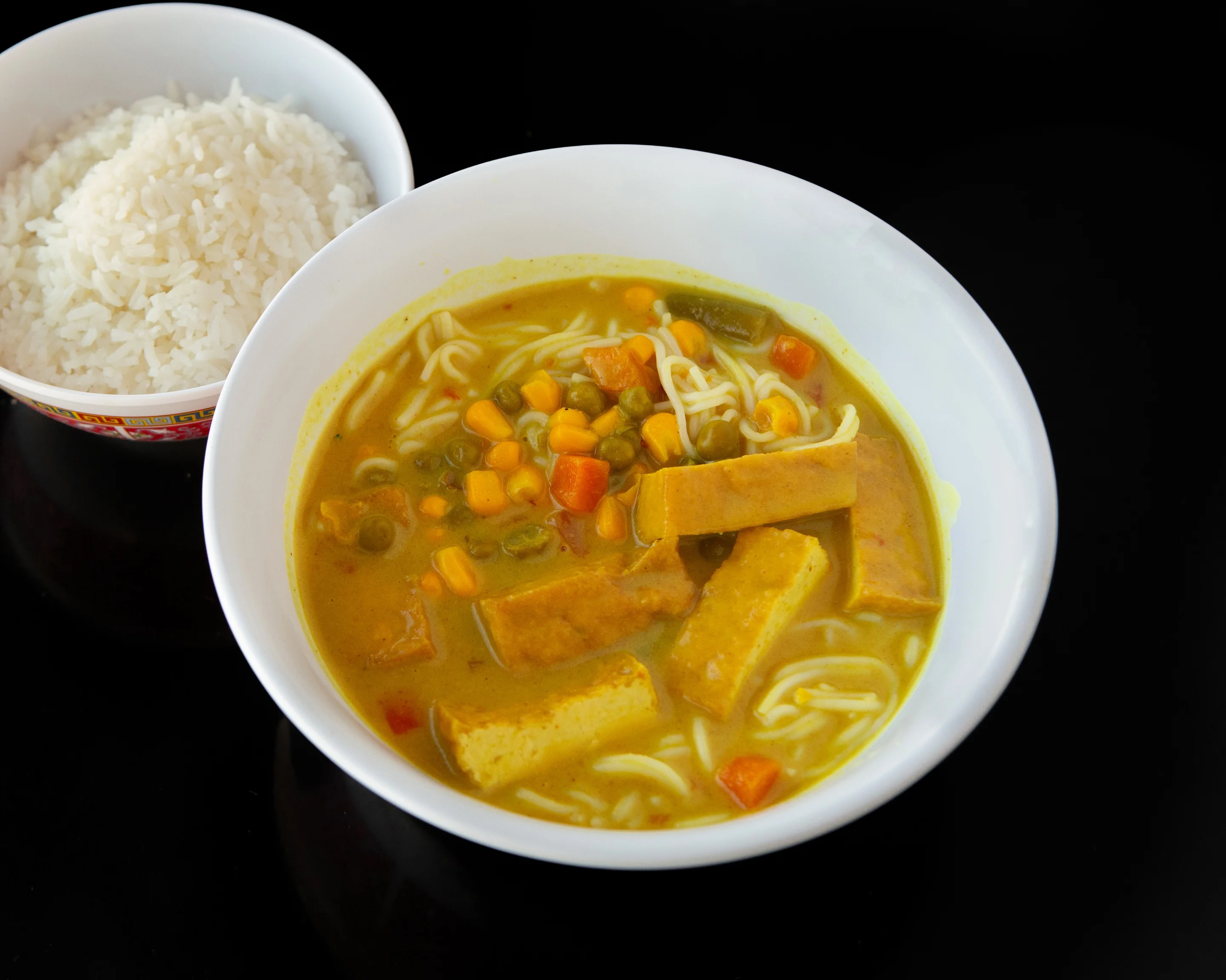 Bowl of Thai curry noodle soup with tofu and vegetables