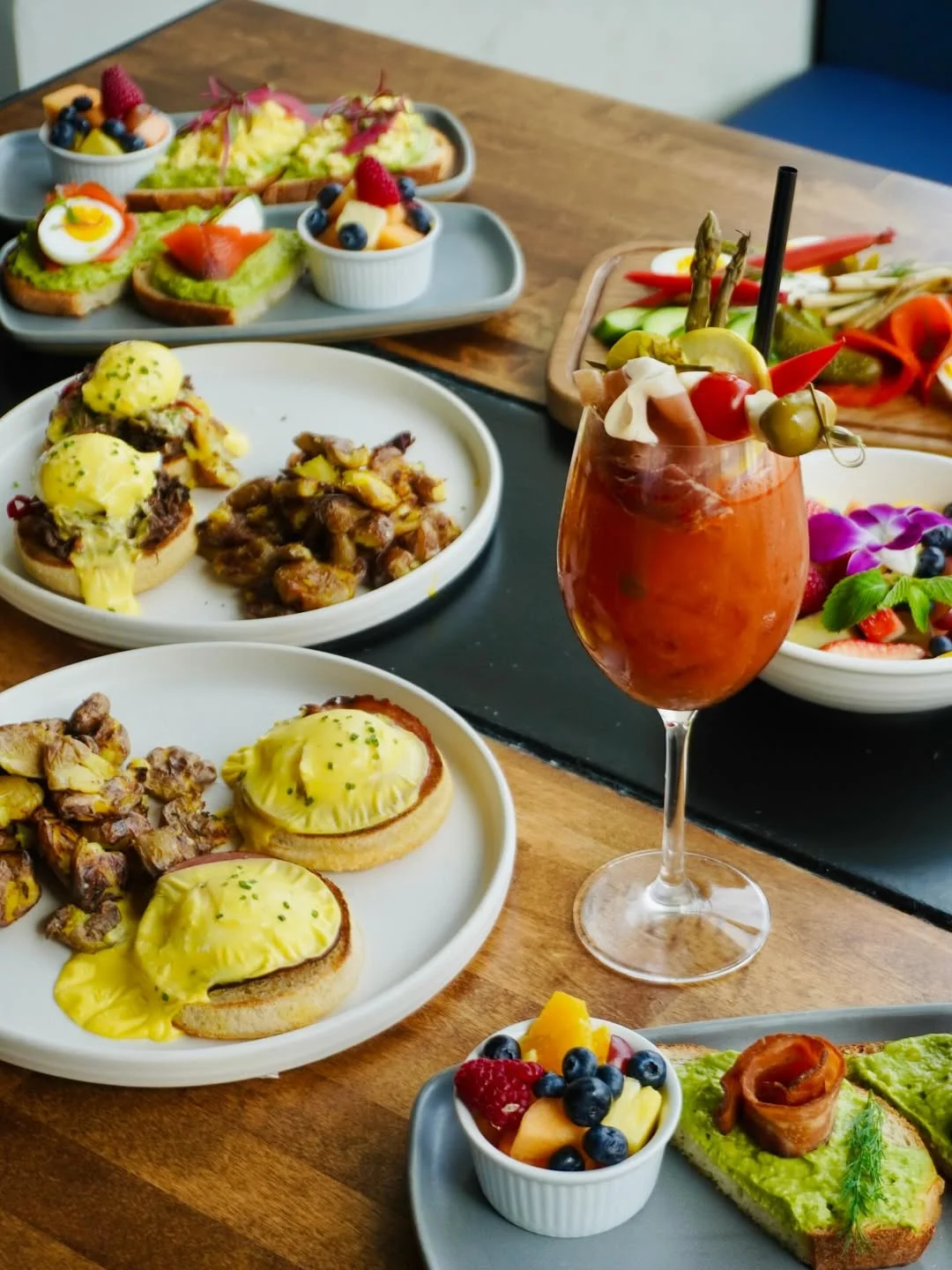 Brunch spread featuring eggs benedict and a vibrant cocktail
