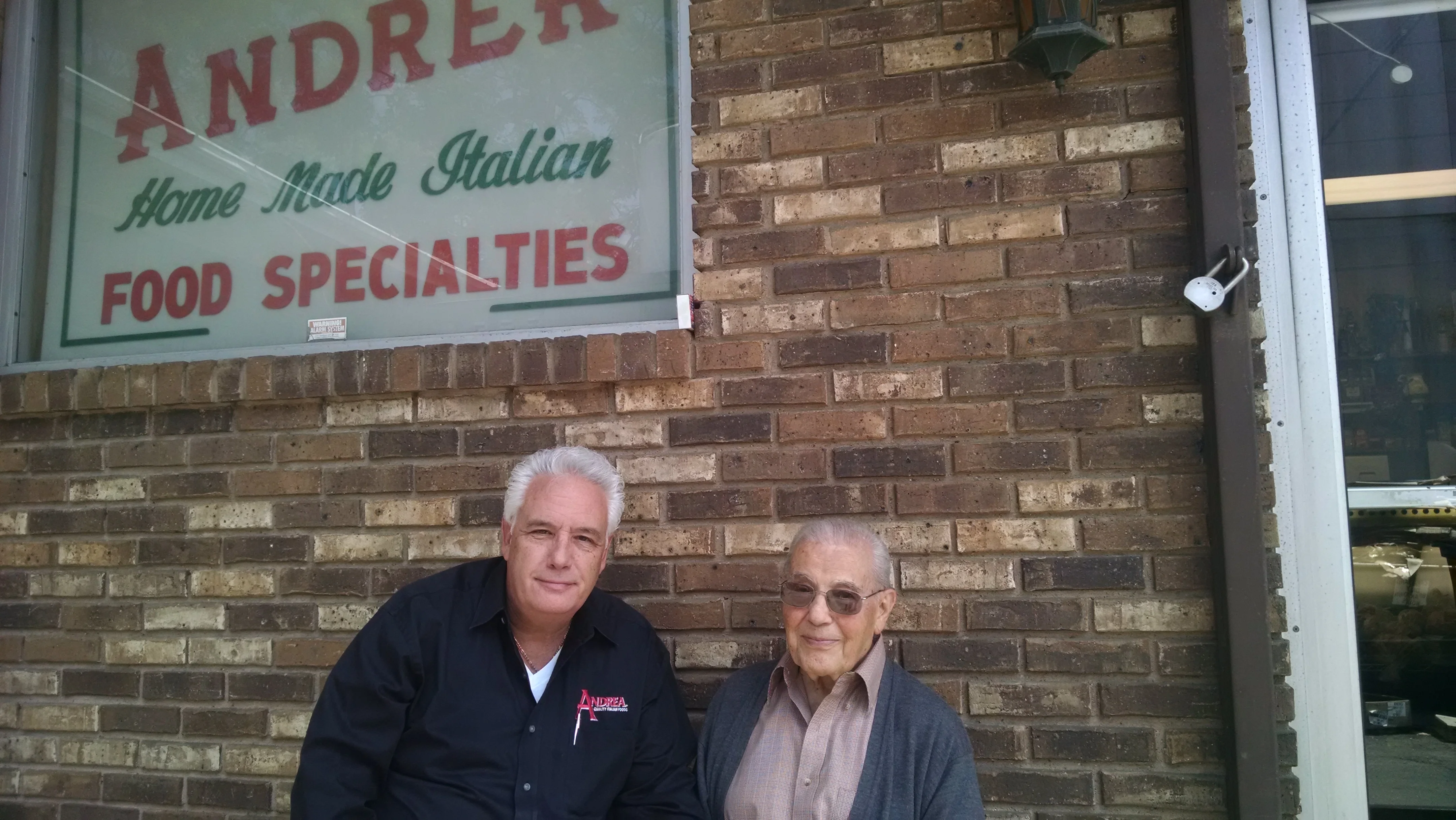 Two people sitting outside an Italian food specialty shop