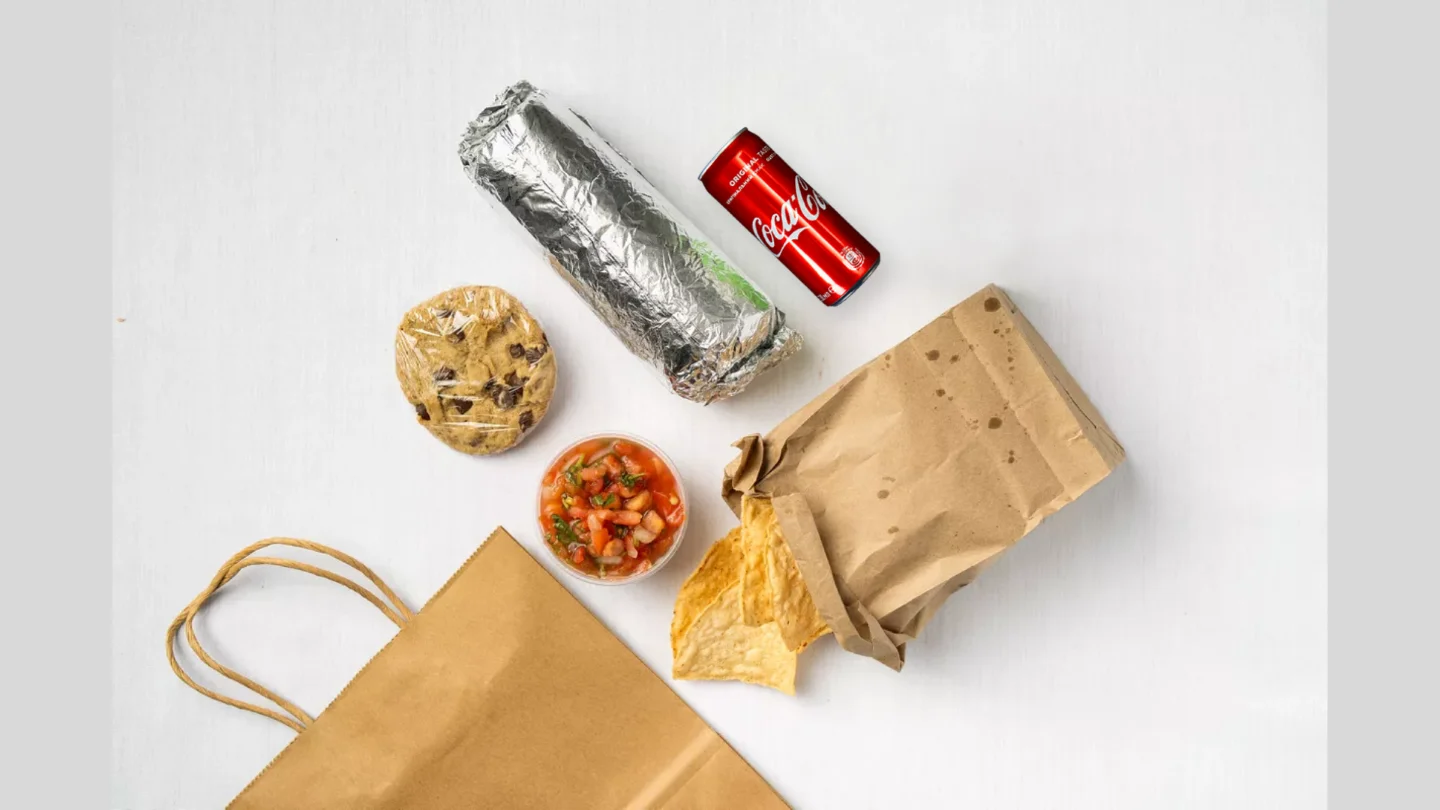 Delicious burrito with chips and salsa in a takeout bag