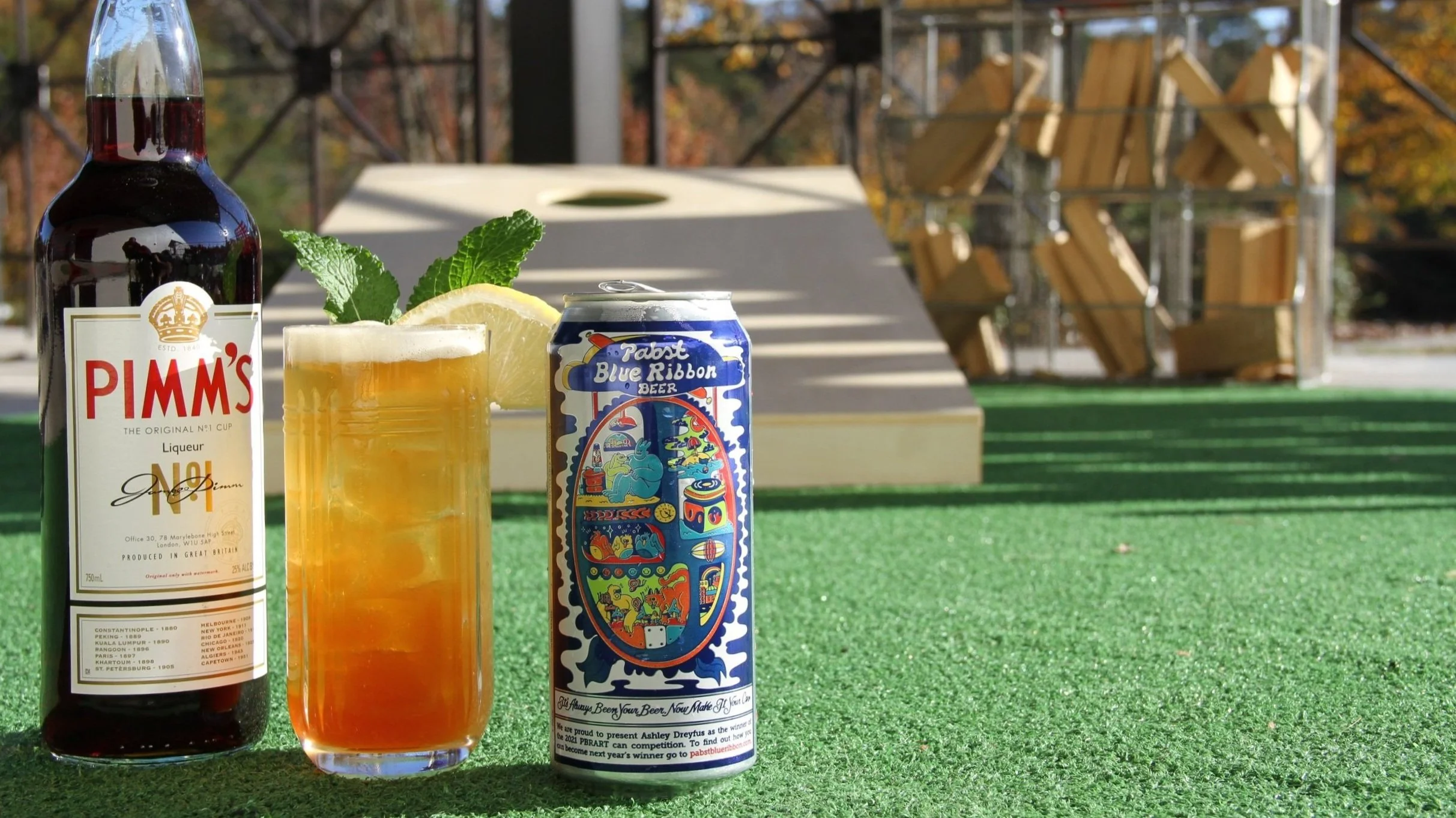 Refreshing Pimm's cocktail with lemon and mint on a green outdoor setting