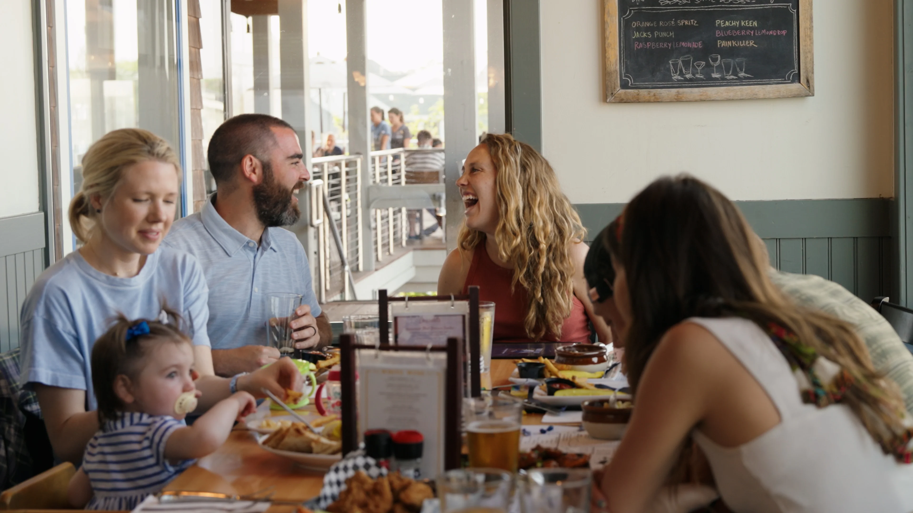 A group of friends gathered around a table, sharing food and laughter, creating a warm and social atmosphere.