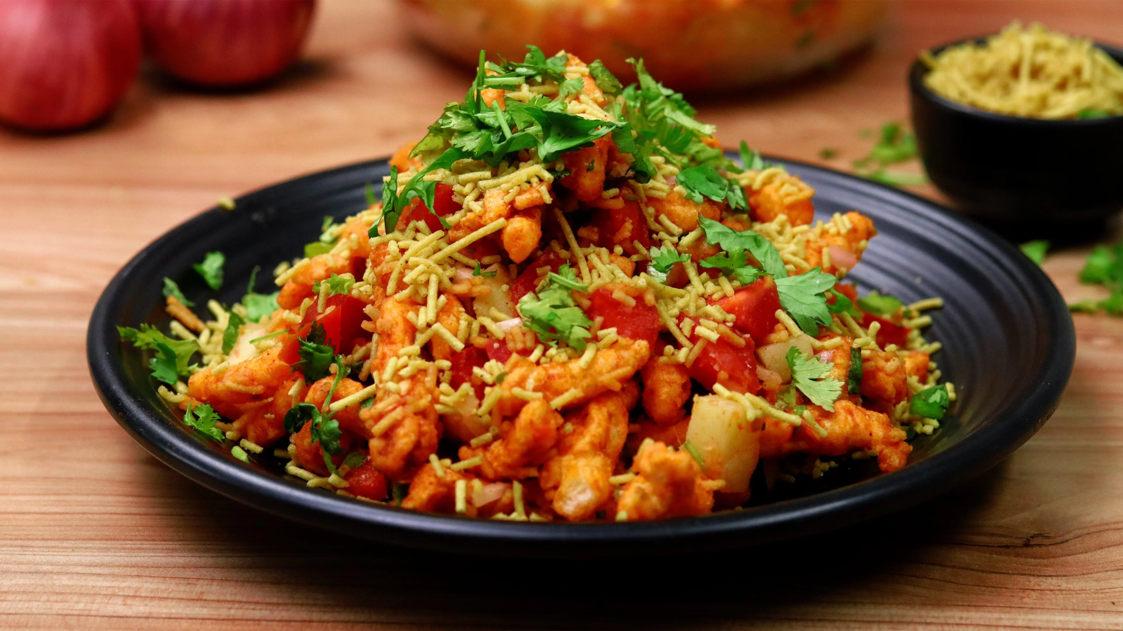 A vibrant dish featuring spiced chicken, diced tomatoes, and fine noodles topped with fresh coriander.