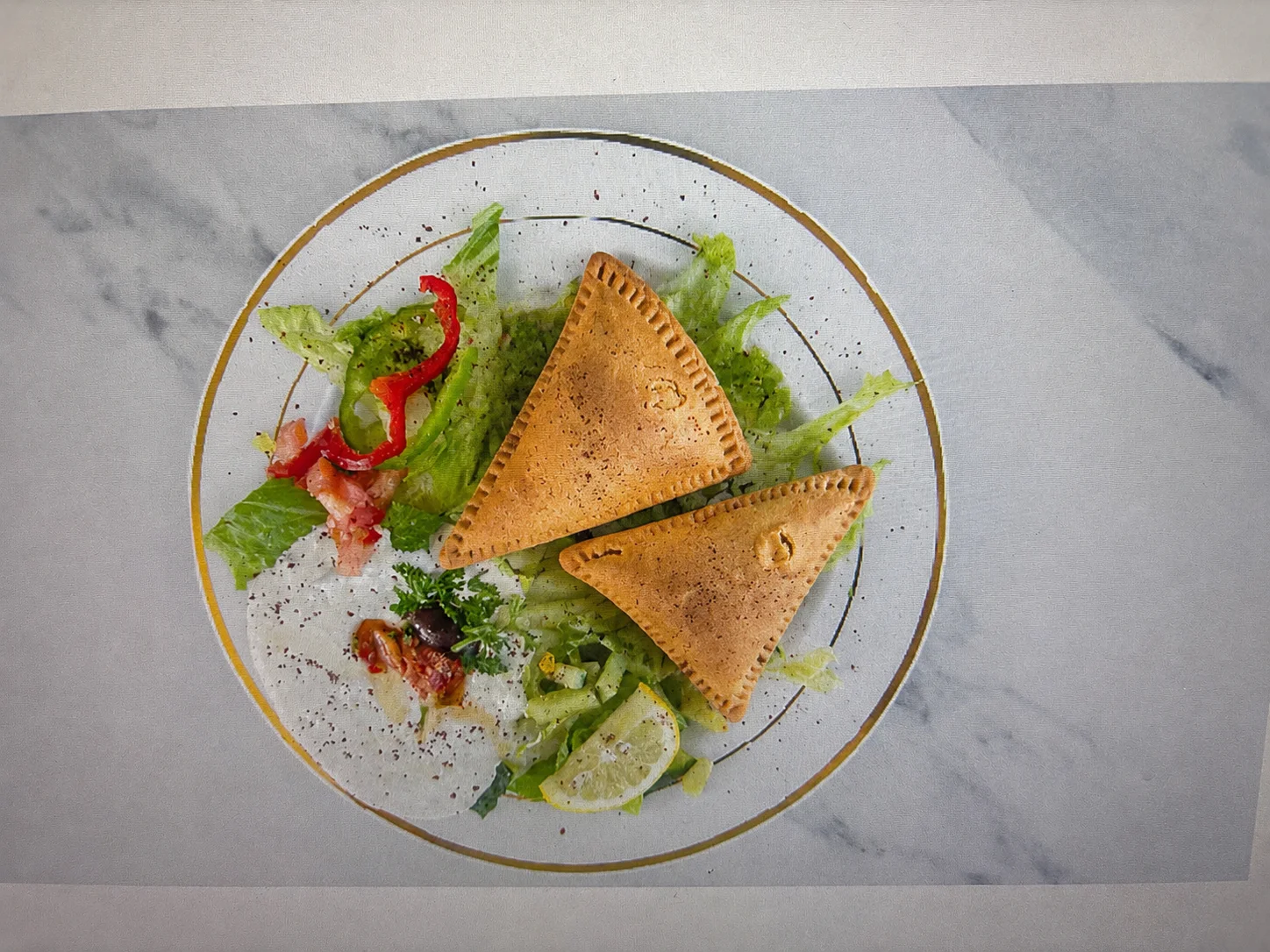 A plate featuring two stuffed pastries served with fresh salad and garnishes including tomatoes and lettuce.