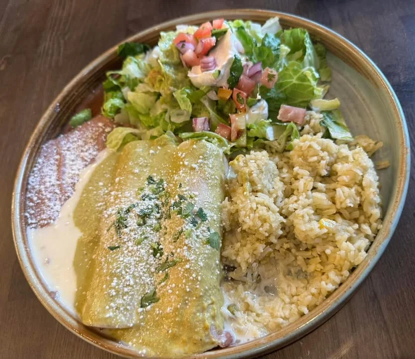 Plate of enchiladas with rice and salad, showcasing Mexican cuisine