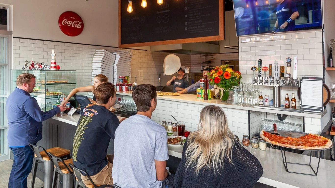 Casual pizzeria interior with patrons enjoying pizza