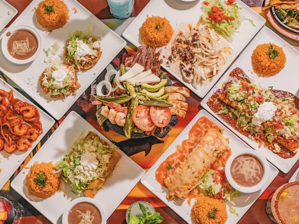 Mexican feast featuring tacos, enchiladas, and grilled shrimp platter