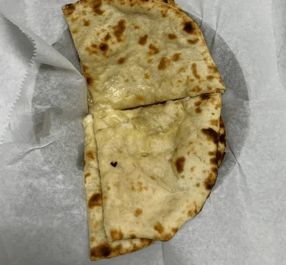 Folded naan bread on white parchment paper.
