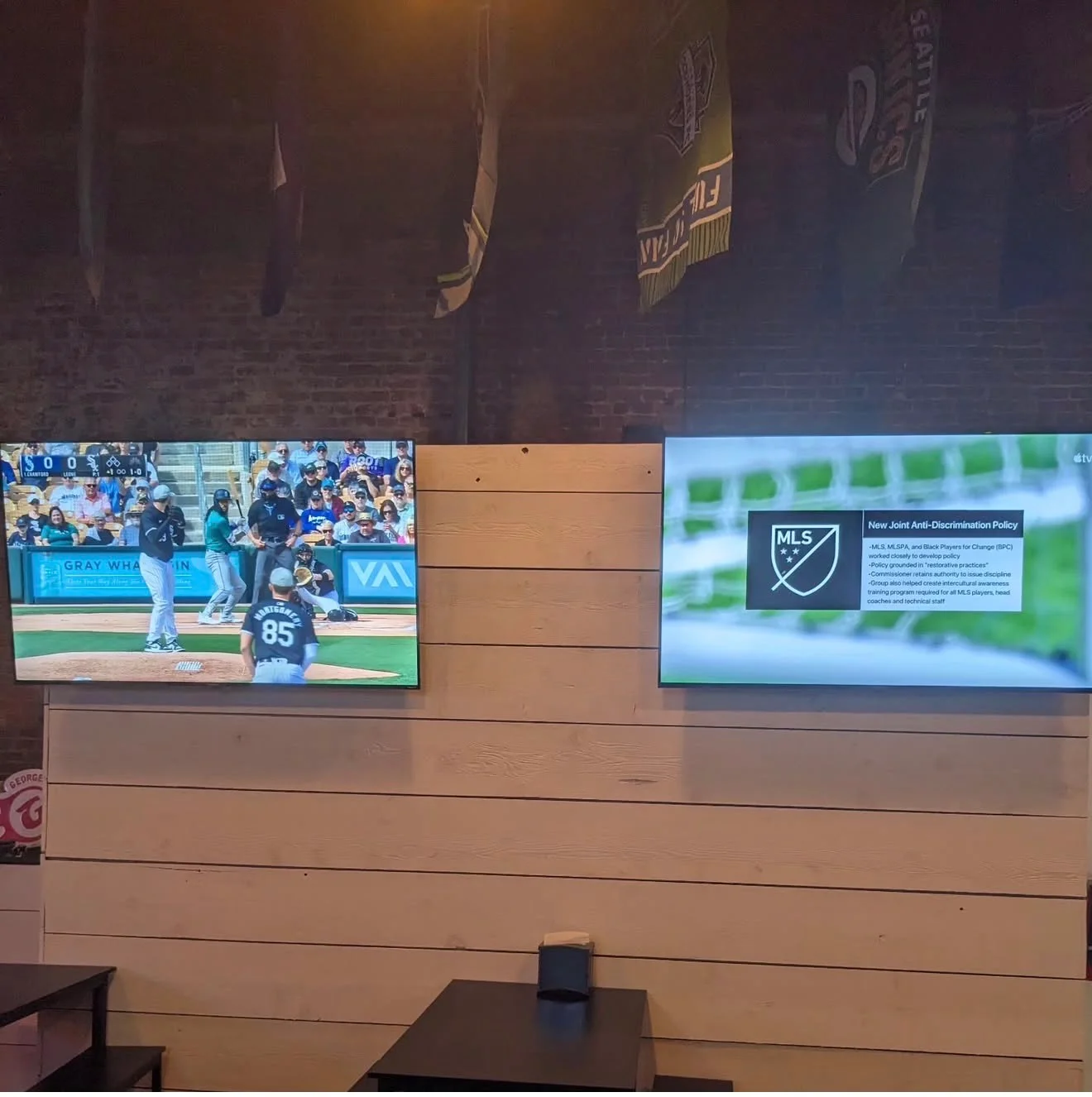 Two wall-mounted screens showing different sports events in a cozy bar environment.