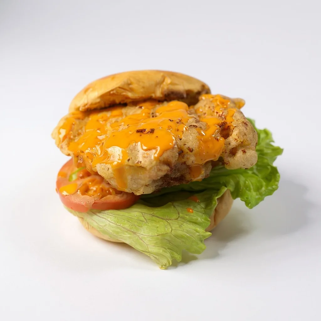A fried chicken sandwich stacked with a crispy chicken patty, melted cheese, lettuce, and tomato, all in a soft bun.
