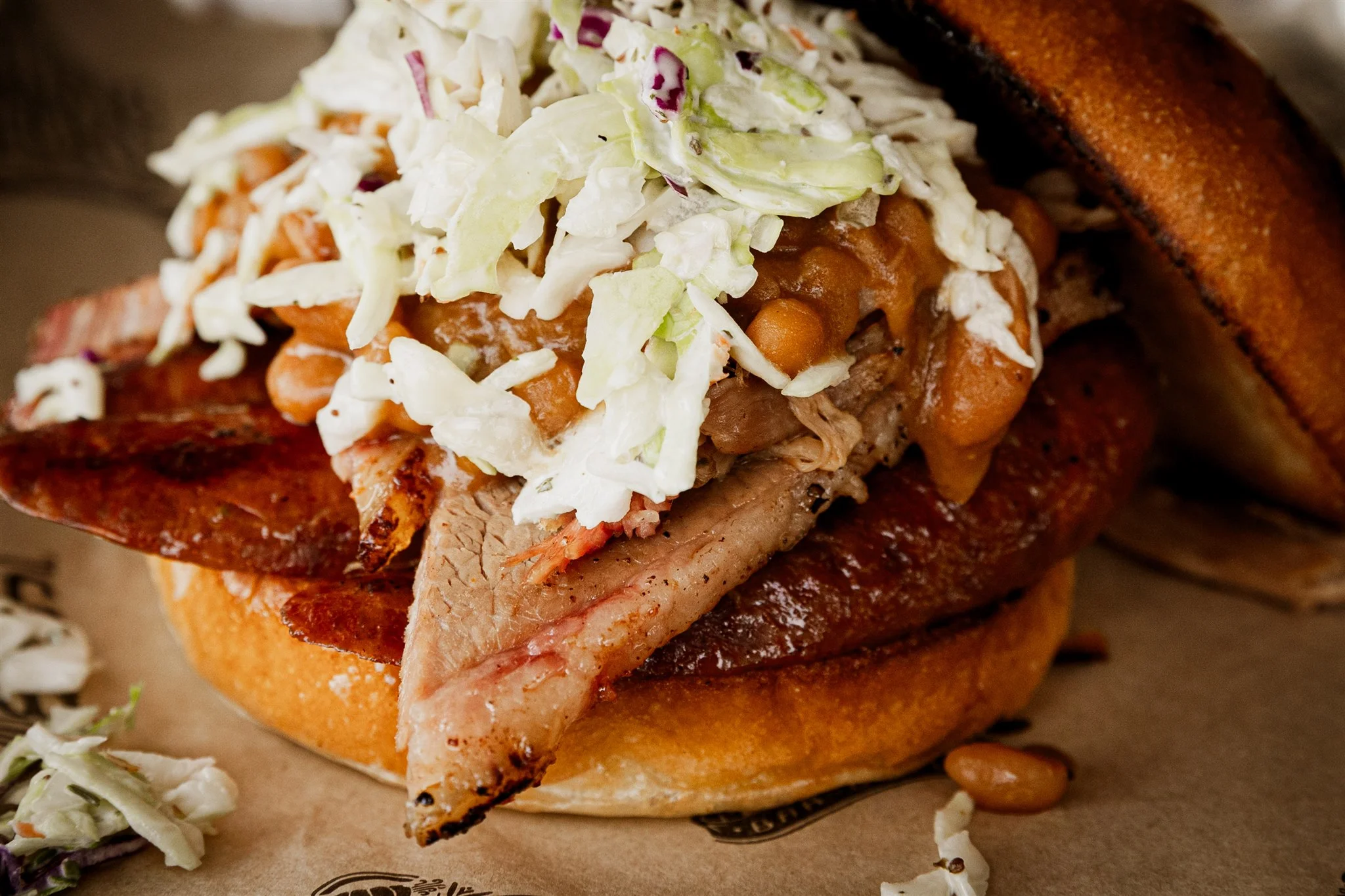 the el jefe sandwich - brisket, pulled pork, and hot link sausage topped with baked beans and coleslaw