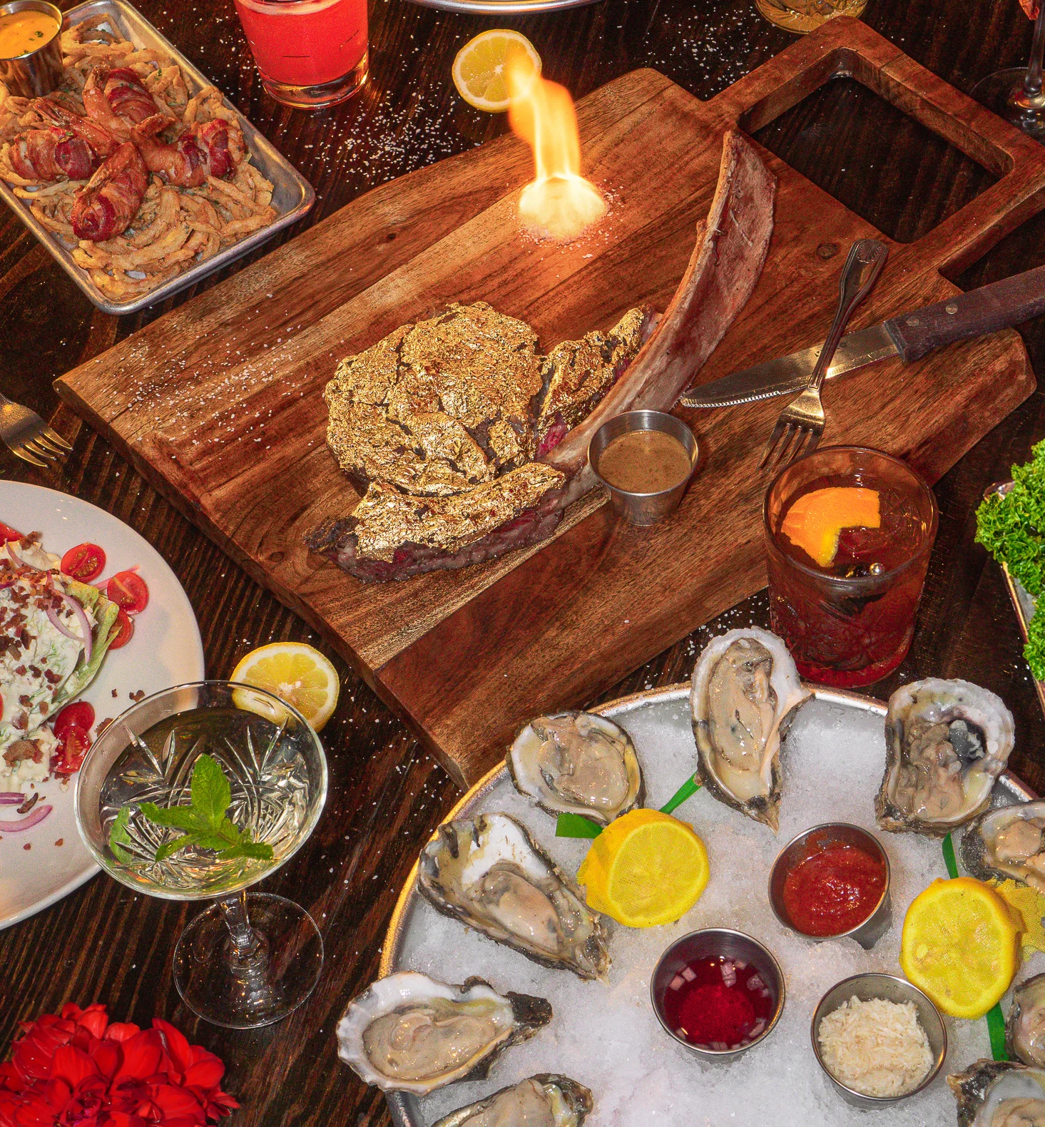 Luxury dinner spread featuring gold-dusted tomahawk steak, oysters, shrimp cocktail, and craft cocktails — dinner Midtown Houston, modern American restaurant Houston, group dining Houston