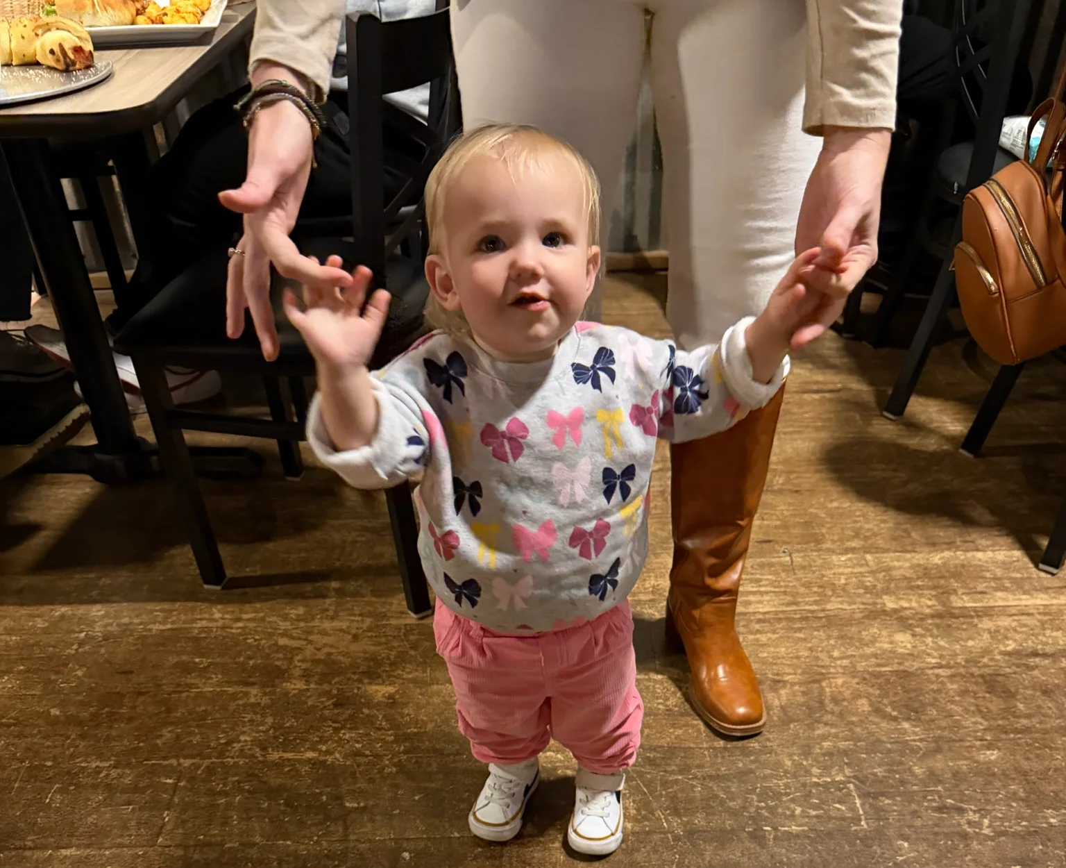 Toddler standing in a restaurant, smiling and reaching out