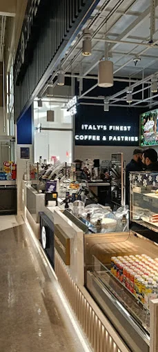 An interior view of a coffee shop showcasing the counter area and displays filled with coffee and pastries.