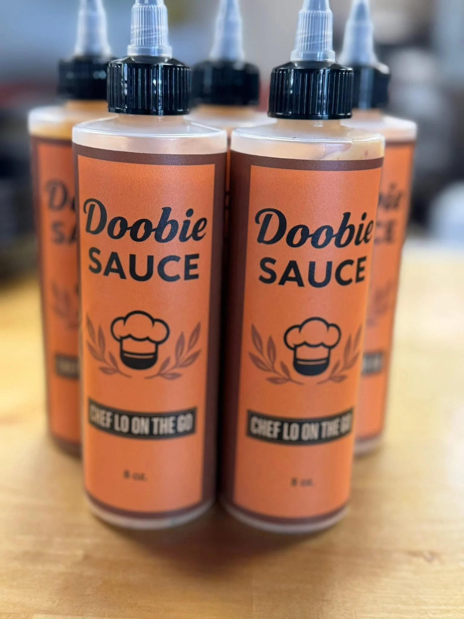 Bottles of Doobie Sauce by Chef Lo on a wooden table