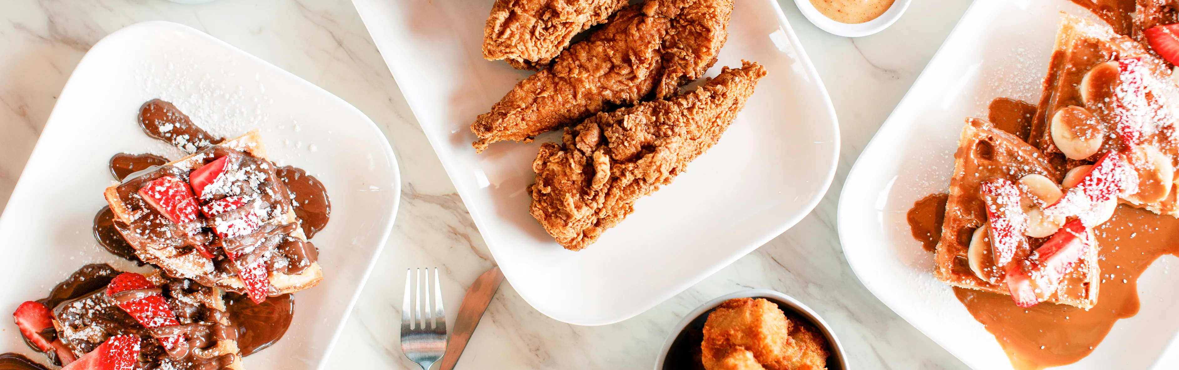 Southern fried chicken and waffles with chocolate sauce and strawberries
