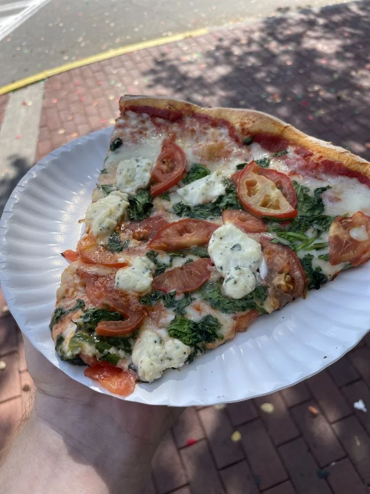Slice of spinach and tomato pizza from a local pizzeria