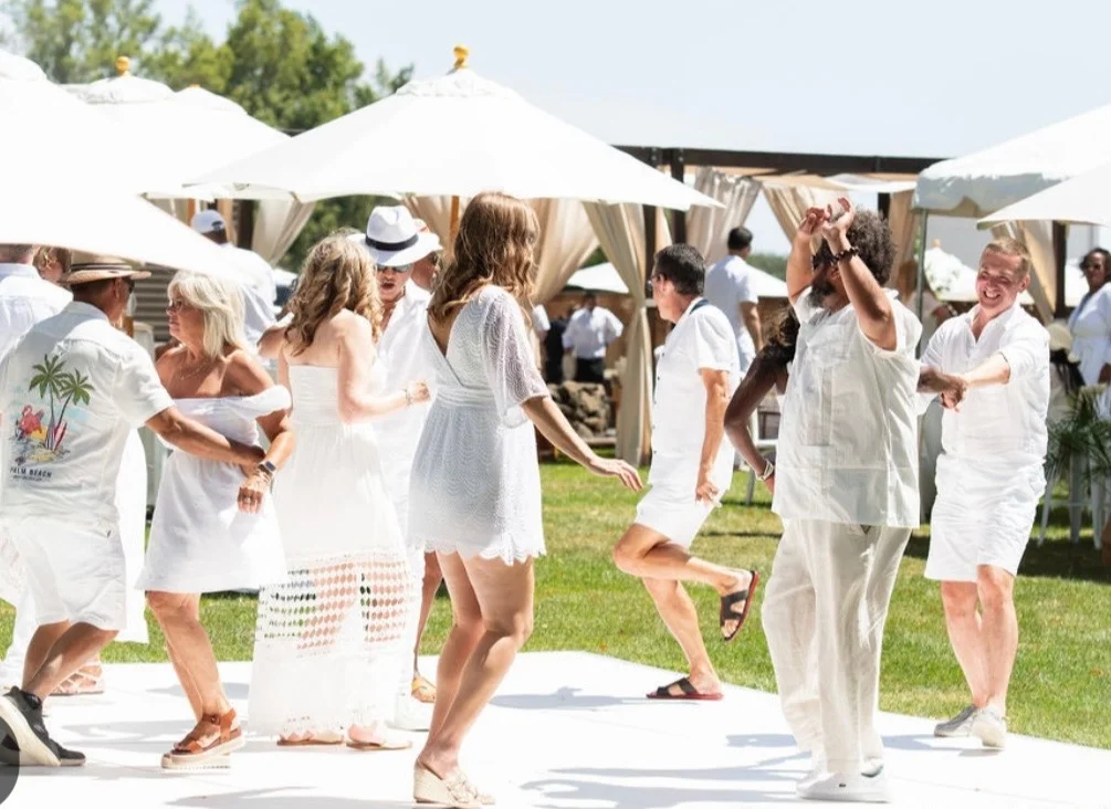 Guests dancing at a lively outdoor event under white umbrellas