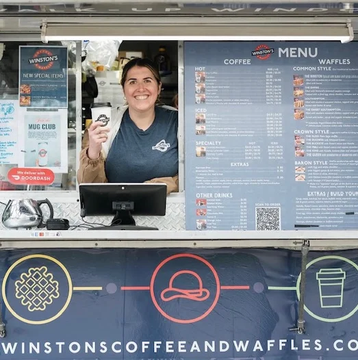 Friendly barista at a coffee truck serving delicious waffles and coffee