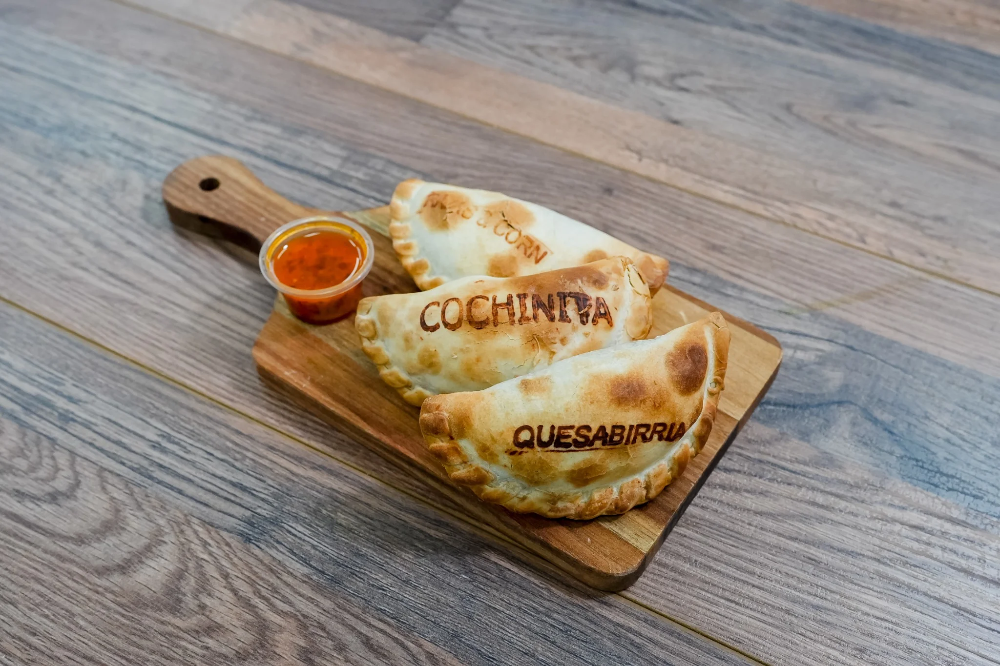 Golden empanadas with edible flowers and dipping sauce