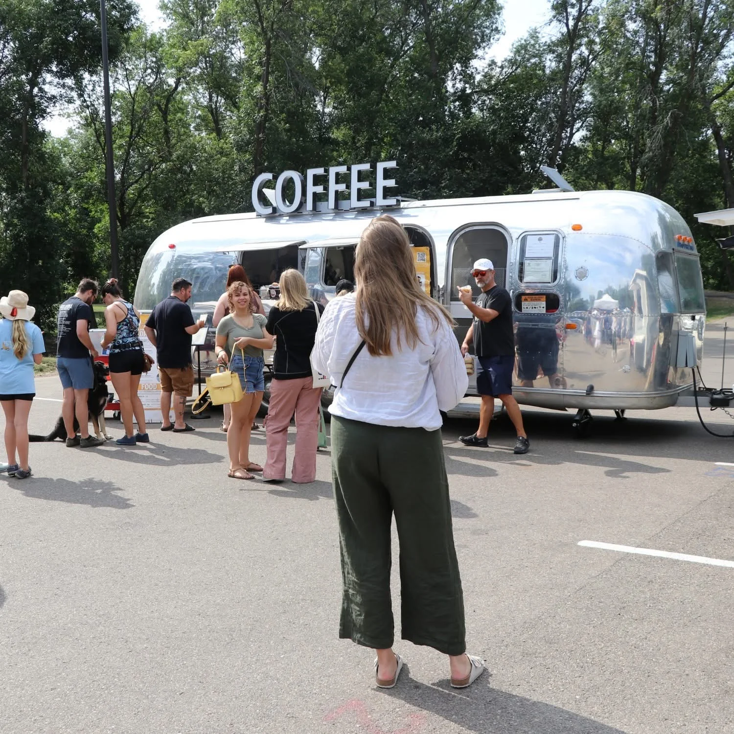 a 1969 airstream trailer with a coffee sign sits in a parking lot.