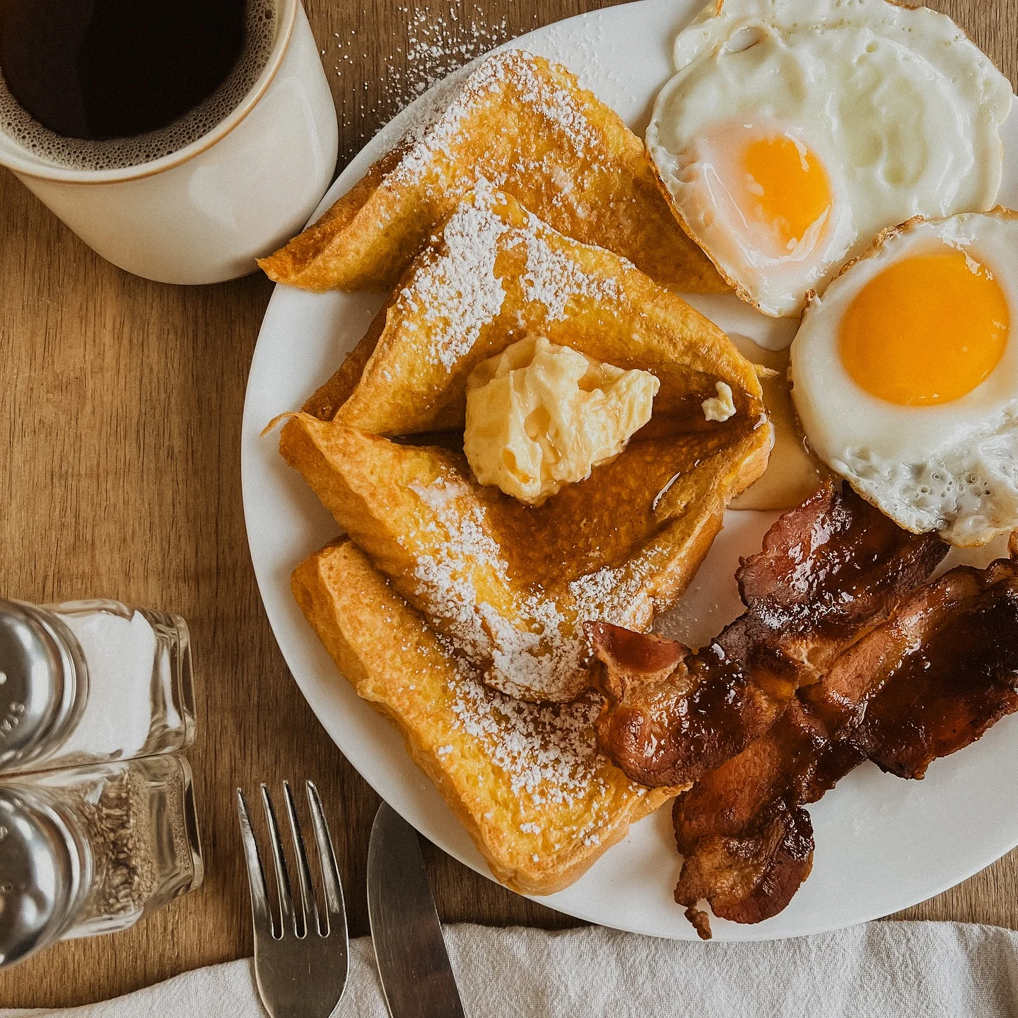 Classic American breakfast with French toast, eggs, and bacon