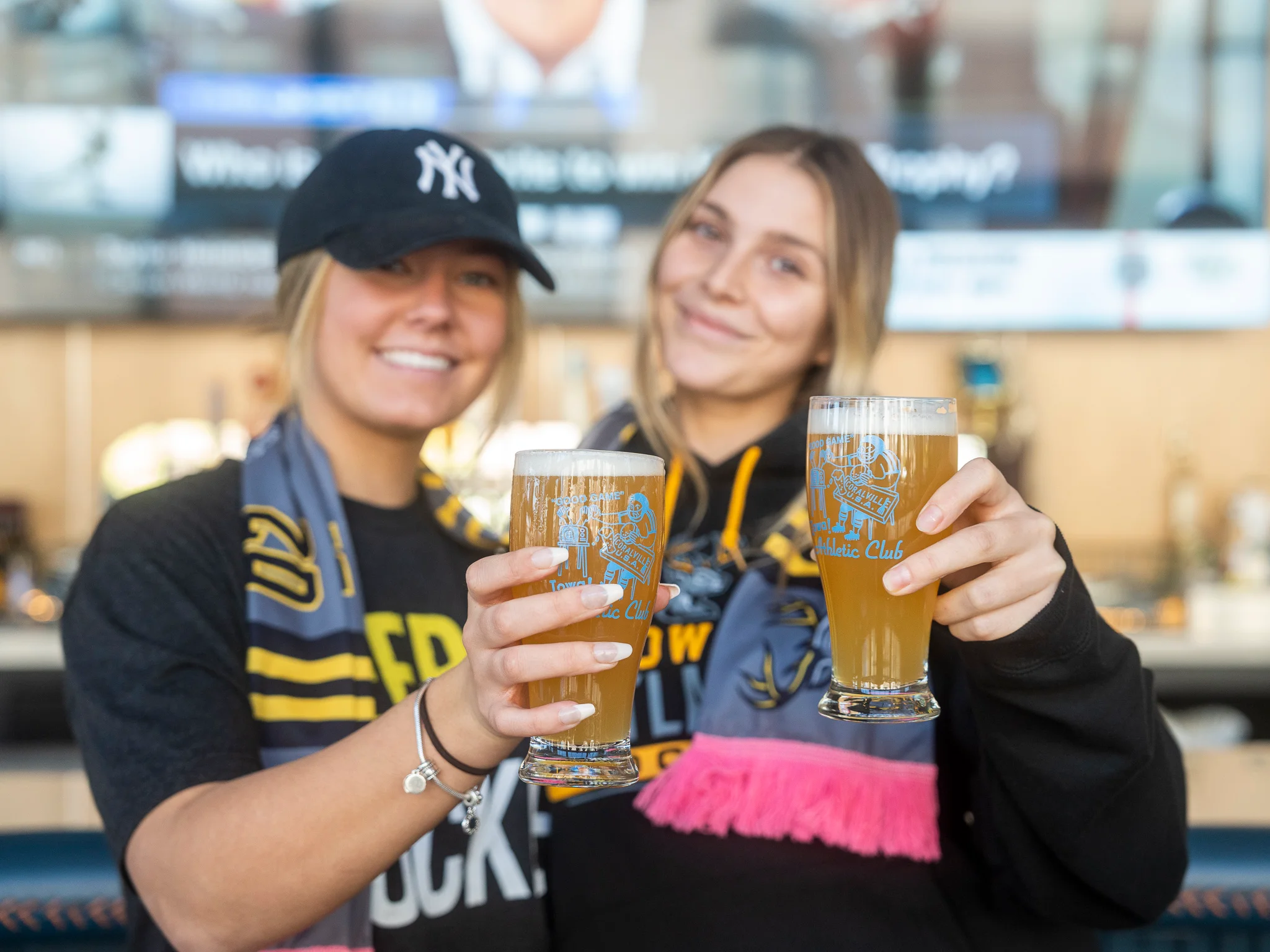 Two friends toasting with craft beers at a lively bar