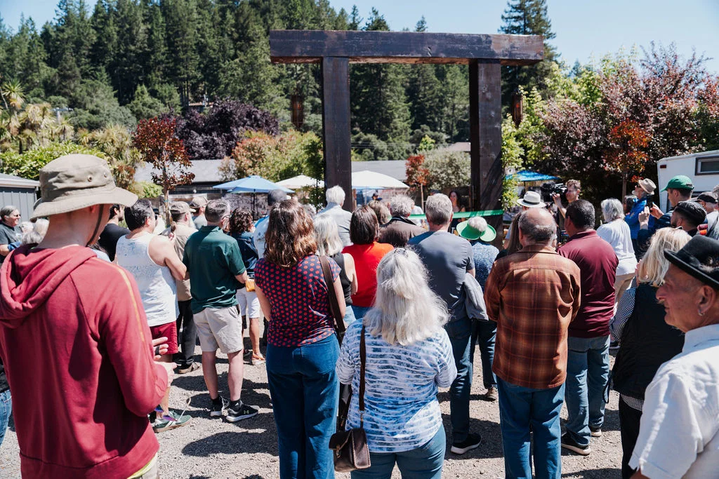 Community gathering at a rustic outdoor venue with a wooden arch
