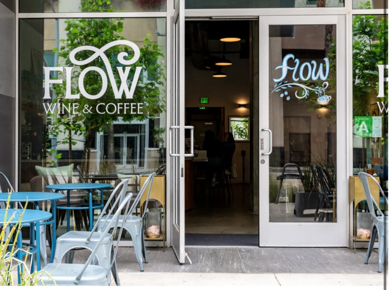 Entrance of Flow Wine & Coffee with outdoor seating and greenery.
