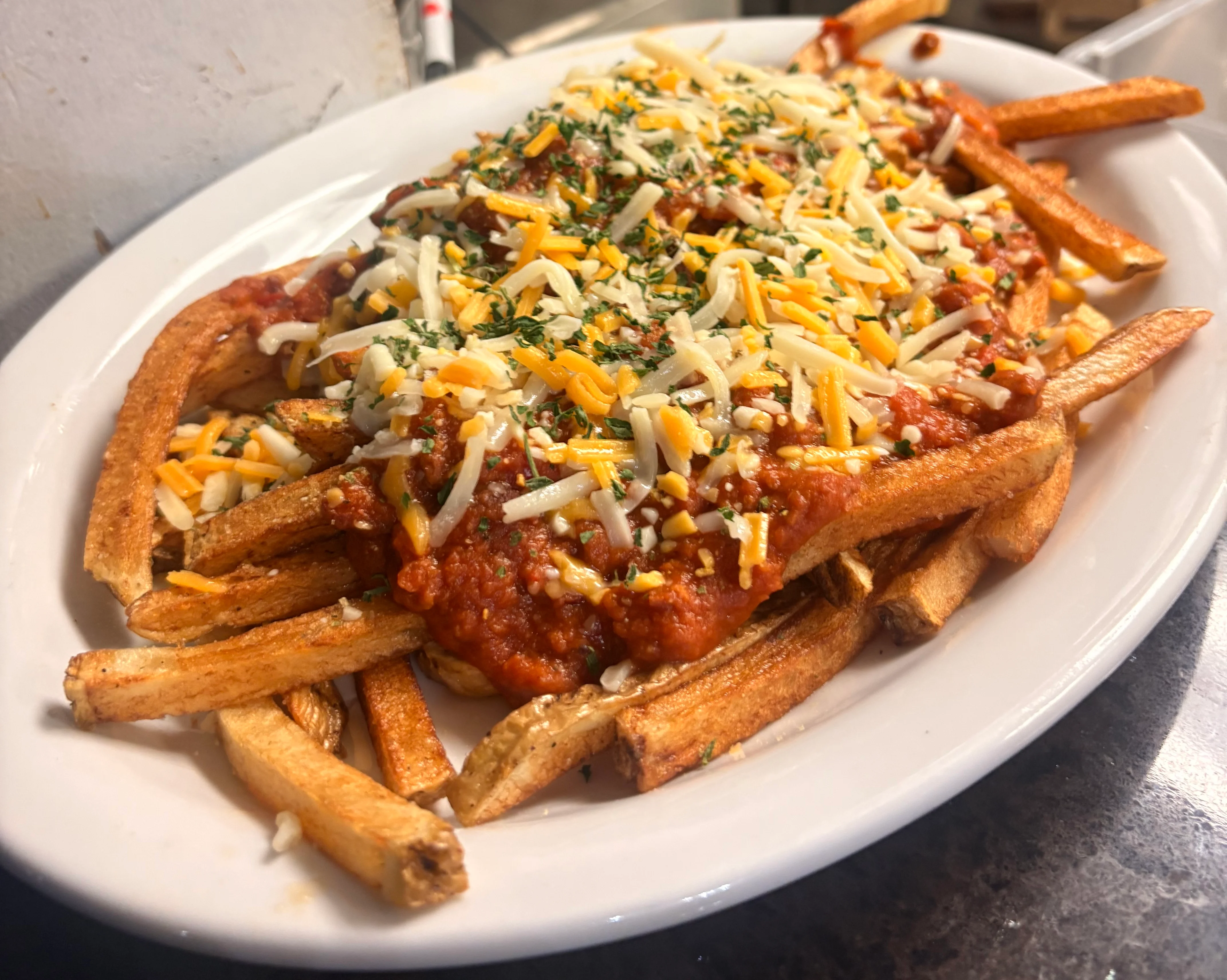 Loaded chili cheese fries topped with melted cheese and herbs