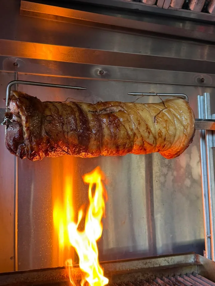 Slow-roasted pork on a spit over open flames