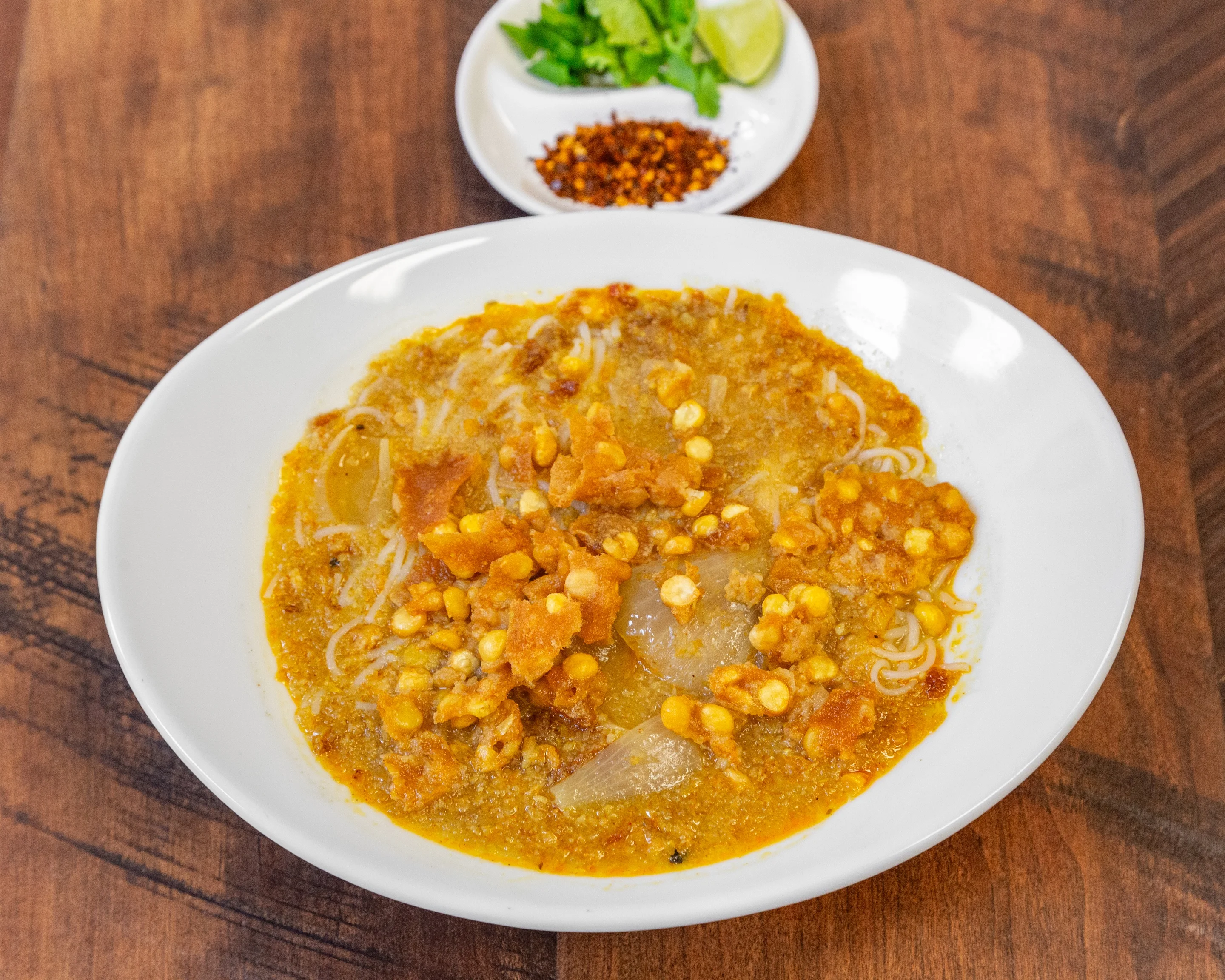 Burmese mohinga served with crispy toppings and lime