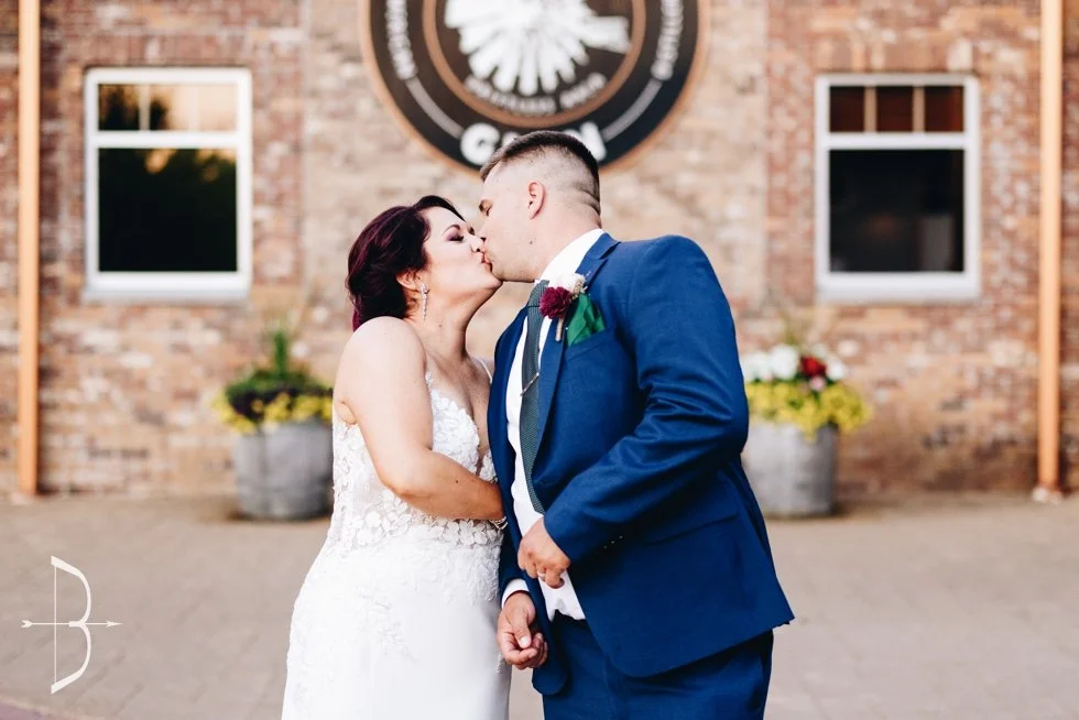 A newly married couple kissing in front of the Driftless Glen entrance sign