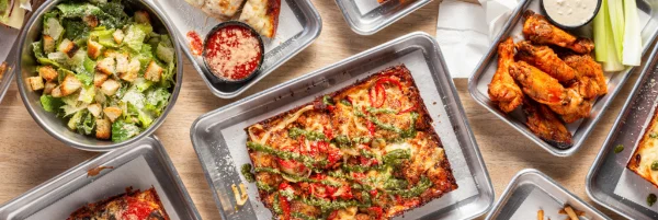 Delicious pizza with toppings and crispy chicken wings